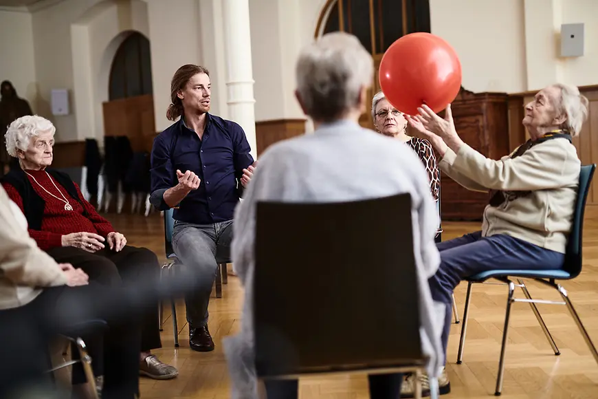 Ältere Menschen in einem Stuhlkreis in einem Saal