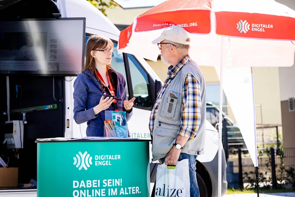 Ein Infostand des Digitalen Engels, an dem eine junge Frau einen älteren Mann berät